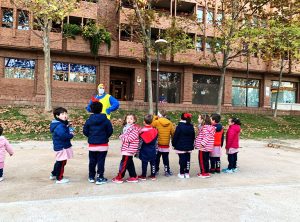 Los niños hacen una fila mientras un payaso está delante de ellos explicándoles el próximo juego a jugar en el parque.
